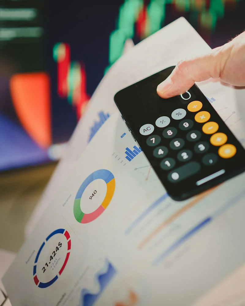 Hand holding a calculator over financial documents